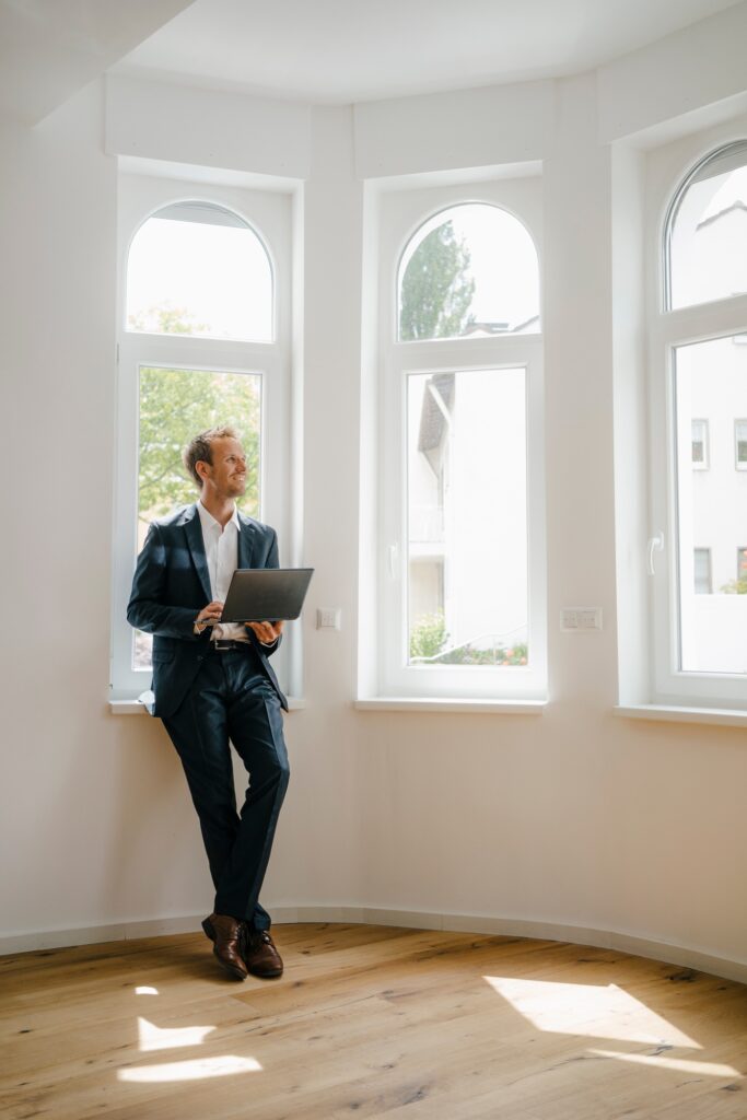 Estate agent waiting in newly refurbished home, holding laptop